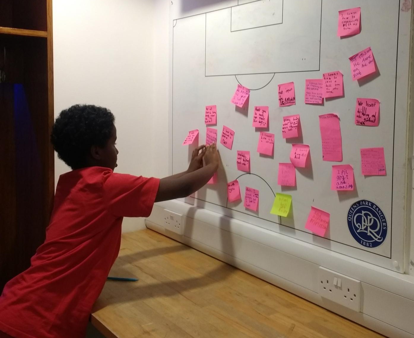 A boy puts a sticky note on a board in an exercise